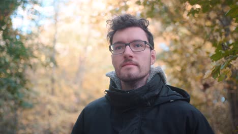 Junger-Europäischer-Mann-Mit-Brille-Und-Bart-Steht-In-Einem-Herbstlichen-Mischwald-Und-Blickt-In-Die-Ferne
