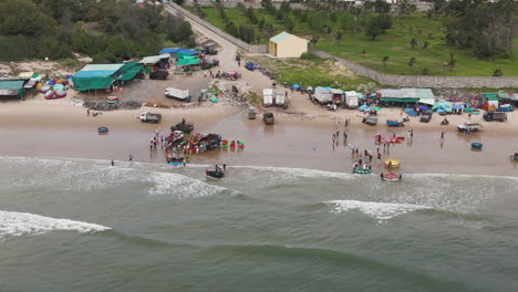 Fishermen-trade-the-harvested-fish-to-local-dealers-at-the-seashore,-aerial-orbital