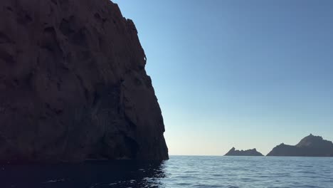 Huge-rock-in-middle-of-sea-at-Scandola-peninsula-nature-reserve-in-summer-season-as-seen-from-moving-boat,-Corsica-island-in-France