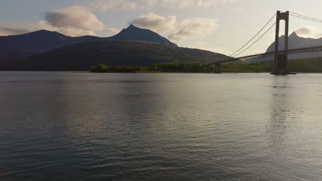 Drohne-über-Dem-Wasser-Im-Fjord-Und-Enthüllt-Eine-Hängebrücke-Und-Eine-Entspannende-Berglandschaft