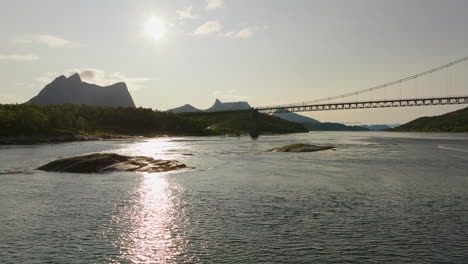 Sun-reflection-over-water-in-Efjorden-with-bridge-and-majestic-mountains-in-background