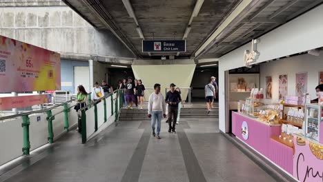 People-saunter-out-of-the-Chit-Lom-Bts-Station-towards-the-skywalk-in-Bangkok,-Thailand