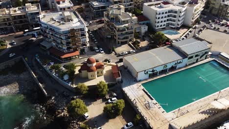 Massive-pool-and-apartment-buildings-of-Rethymno,-aerial-orbit-view