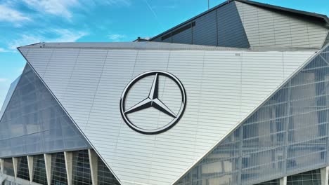 Close-up-drone-shot-showing-german-Mercedes-Benz-Logo-on-modern-facade-of-Stadium-in-Atlanta-City,-America---backwards-flight