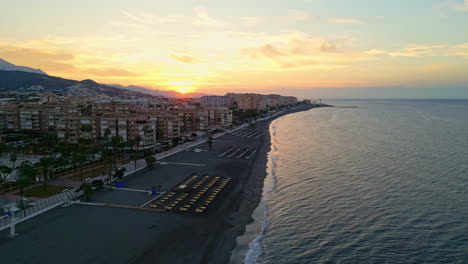 Aerial-drone-forward-moving-shot-over-beautiful-beach-front-along-the-coastal-town-of-Fuengirola-in-Malaga,-Spain-at-sunrise