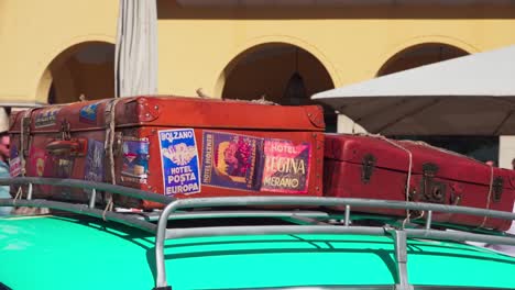 Side-view-of-vintage-suitcase-on-a-car-roof-luggage-rack-exhibited-during-a-classic-car-meeting-in-Bozen---Bolzano,-South-tyrol,-Italy