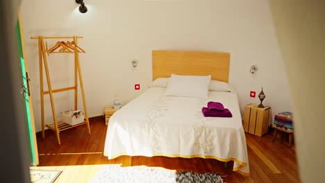 Small-furnitured-bedroom-with-wooden-floor,-decoration,-view-shot-through-object