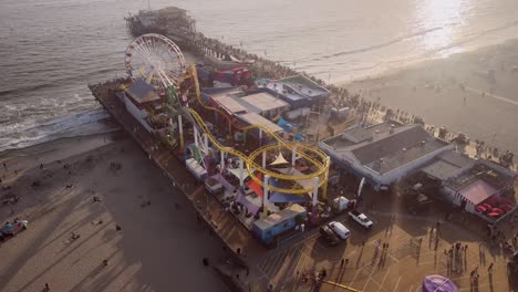 A-scenic-view-of-the-Santa-Monica-amusement-park-at-sunset,-with-ocean-waves-lapping-at-the-shoreline
