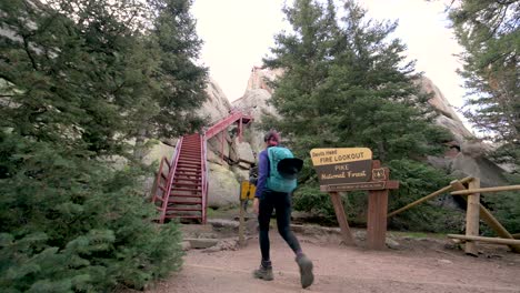 Hikers-at-the-base-of-the-Devil’s-Head-Fire-Lookout-stairs-with-National-Forest-sign,-static