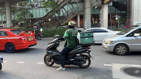 Agarra-Al-Ciclista-De-Comida-Dando-Marcha-Atrás-Con-Seguridad-A-Su-Motocicleta-En-El-Tráfico-Que-Viene-En-Sentido-Contrario-En-Bangkok,-Tailandia