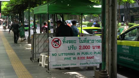 Law-enforcement-officers-set-up-a-tentage-and-displayed-signs-in-Thai-and-English,-'No-Littering-In-Public-Place,-Fine-is-2000-Baht'-in-the-Sukhumvit-area,-Bangkok,-Thailand