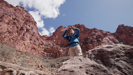 Young-male-tourist-takes-a-photo-on-his-phone's-camera-during-a-hike-in-the-Grand-Canyon-Arizona-desert