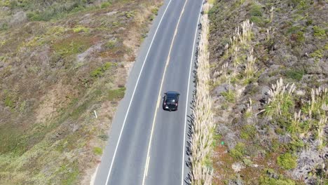 Aerial-video-of-a-highway,-black-car-driving-through,-camera-sightly-goes-up,-in-Pescadero-Coast,-San-Mateo-California