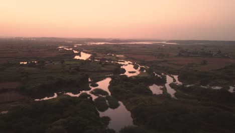 Luftdrohnenaufnahme-Eines-Kleinen-Flusses-Durch-Landwirtschaftliche-Felder-In-Nordindien-Während-Des-Sonnenuntergangs-In-Der-Dämmerung