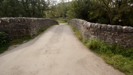 Mid-shot-of-road-going-over-the-stone-bridge-at-Wetton-mill