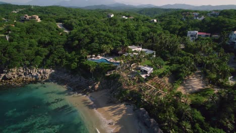 Aerial-view-of-Huatulco-beach,-lush-forest,-and-homes,-Mexico