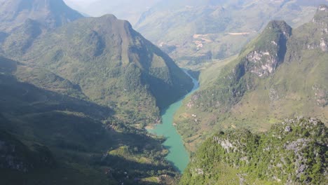 Drone-moves-forward-over-rocky-karst-mountain-reveal-twisty-green-Nho-Que-river-between-mountain-ranges-Ha-Giang-Viet-Nam