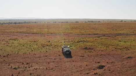 Toma-Aérea-De-Un-Fotógrafo-De-Vida-Silvestre-Conduciendo-Un-Vehículo-De-Safari-En-La-Sabana-De-La-Reserva-Nacional-De-Maasai-Mara,-Kenia,-áfrica-Con-Hermosos-Paisajes,-Conservación-Del-Norte-De-Masai-Mara