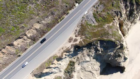 Top-view-drone-video,-of-a-road-driven-by-cars-and-buses,-aside-captured-the-coastline-in-San-Mateo,California