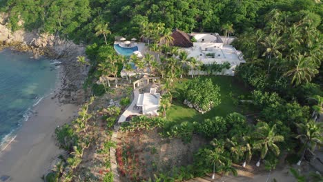 Aerial-view-of-luxury-villa-in-Huatulco,-Mexico-beside-a-pristine-beach