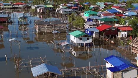 A-fishing-village-made-up-of-lots-of-small-colourful-buildings,-all-on-stilts,-on-a-calm-lake