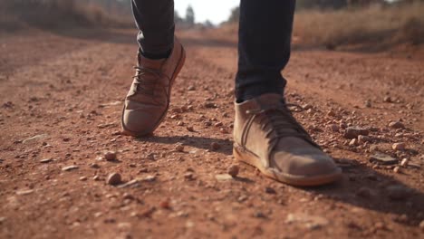 Brown-leather-boots-walking-on-dirt-road