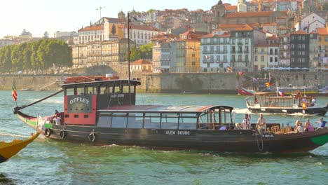 Shot-of-motorboat-moving-on-Douro-river-in-Vila-Nova-de-Gaia,-Porto,-Portugal-during-evening-time