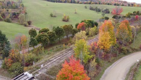 Aerial-flying-passing-railway-in-countryside-during-autumn,-Caledon,-Canada