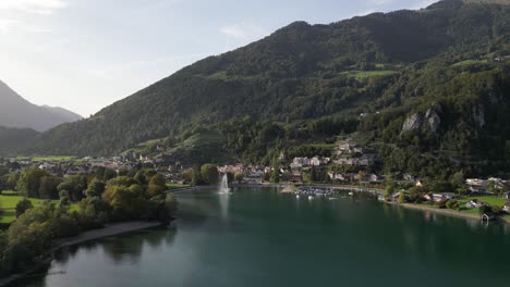 Drone-flies-forward-over-Weesen-town-based-near-shore-of-Walensee-lake,-Switzerland