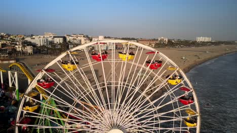 An-exceptionally-close-drone-shot-of-the-Ferris-wheel,-with-beachgoers-who-cannot-be-identified