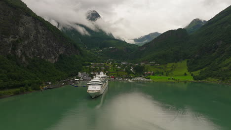 Drone-arc-shot-of-cruise-ship-docked-in-scenic-fjord,-Geiranger,-Norway