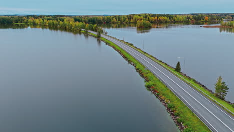 Wide-shot-of-a-land-bridge-road-highway-with-cars-crossing-a-lake-in-Valkeakoski,-Finland