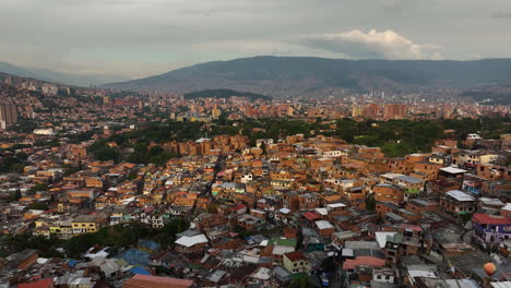Toma-Aérea-De-Seguimiento-Con-Vista-A-Los-Barrios-Marginales-De-La-Comuna-13,-Atardecer-En-Medellín,-Colombia.