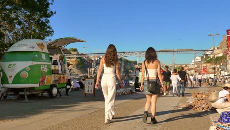 Vila-Nova-de-Gaia,-Portugal:-People-walking-on-the-street-with-Dom-Luis-I-Bridge-in-the-background-over-Douro-River-in-Gaia-city,-Porto,-Portugal