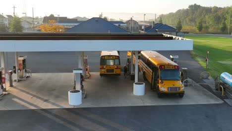 Yellow-school-buses-refueling-at-small-town-gas-station-in-America-after-driving-route-with-students