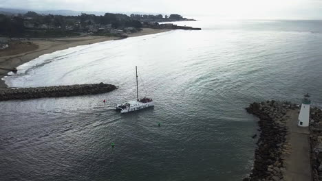 Aerial-tracking-shot-of-a-sailboat-leaving-Santa-Cruz,-in-cloudy-California,-USA