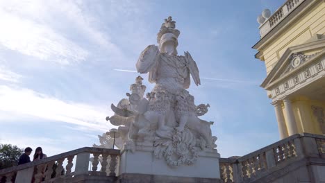 Approaching-a-statue-of-the-Gloriette-Pavilon-on-a-sunny-day-at-Schönbrunn-Palace,-Vienna,-Austria---October-2023