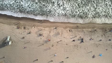 Eine-Drohnen-Luftaufnahme-Des-Strandes-Von-Santa-Monica-Mit-Unbekannten-Personen-Und-Wellen,-Die-Sich-Entlang-Der-Küste-Brechen