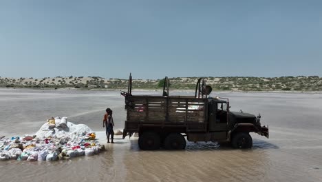 Aerial-Circle-Dolly-Of-Workers-Loading-Up-Bags-On-Back-On-Truck-On-Salt-Lake-In-Sindh