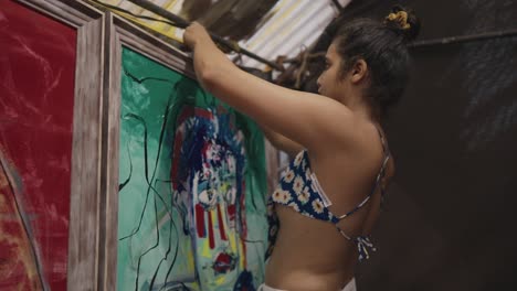 Chica-Colgando-Pinturas-Al-Agua-En-Marcos-En-La-Pared-De-Una-Galería-De-Arte