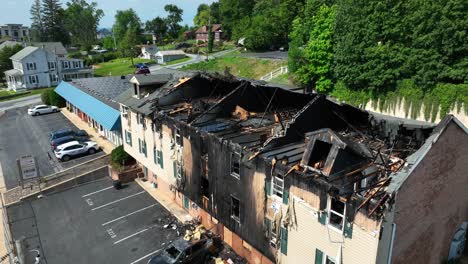 Aerial-view-of-a-burned-apartment-building-in-the-USA-with-charred-walls,-collapsed-roof,-and-nearby-cars