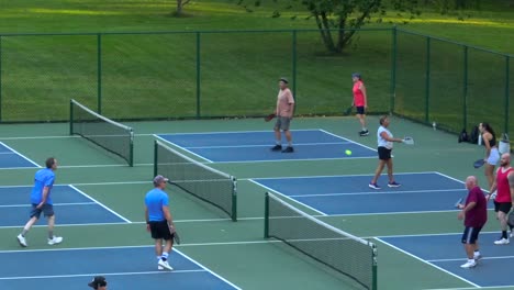 Players-engage-in-a-lively-game-of-pickleball-on-outdoor-courts,-with-swift-moves,-paired-teamwork-in-a-American-park
