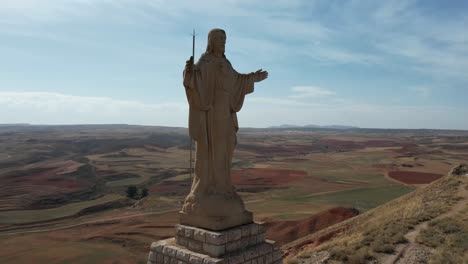 Round-drone-flight-around-a-huge-Jesus-Christ-statue-in-Spain,-in-an-Atumn-afternoon