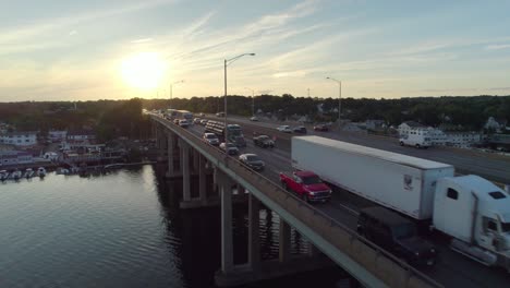 Drone-Shot-Tracking-Forward-over-Interstate-on-Bridge-at-Sunset,-with-Heavy-Rush-Hour-Traffic-and-Trucks