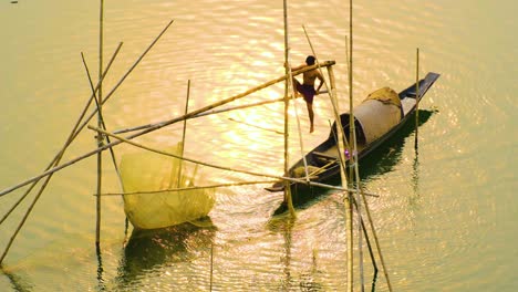 Dorfjunge-Fängt-Bei-Sonnenuntergang-Fischernetze-Vom-Boot-Im-Fluss