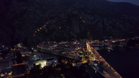 Night-aerial-view-of-Kotor,-Montenegro,-with-illuminated-streets-and-bay