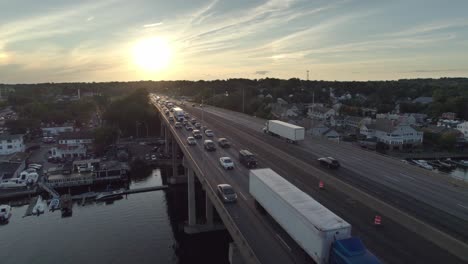 Drone-Shot-Pulling-Back-over-Interstate-on-Bridge-at-Sunset,-with-Heavy-Traffic