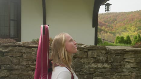 Female-musician-walks-walled-lane-rustic-village-admires-autumn-view