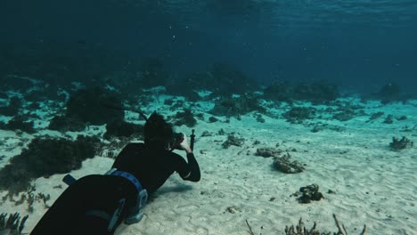 Marine-Biologist-on-ocean-floor-with-camera-capturing-aquatic-life