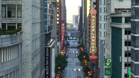 Downtown-Chicago-street-lined-by-towering-buildings,-neon-signs-like-Nederlander,-and-bustling-traffic-at-dusk